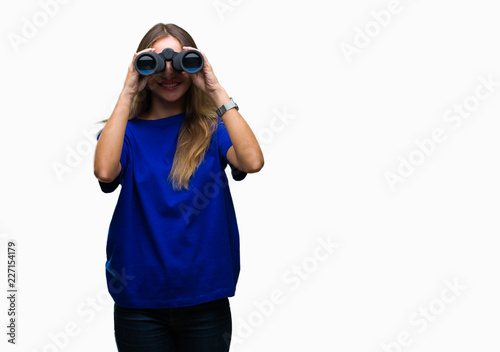 Young beautiful blonde woman looking through binoculars over isolated background with a happy face standing and smiling with a confident smile showing teeth