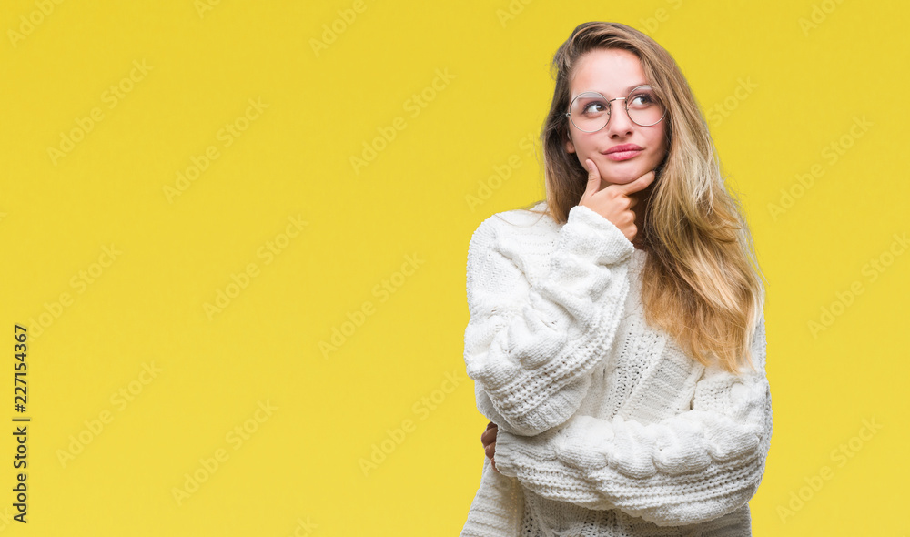 Young beautiful blonde woman wearing winter sweater and sunglasses over isolated background looking confident at the camera with smile with crossed arms and hand raised on chin. Thinking positive. Young beautiful blonde woman wearing winter sweater and sunglasses over isolated background looking confident at the camera with smile with crossed arms and hand raised on chin. Thinking positive.
