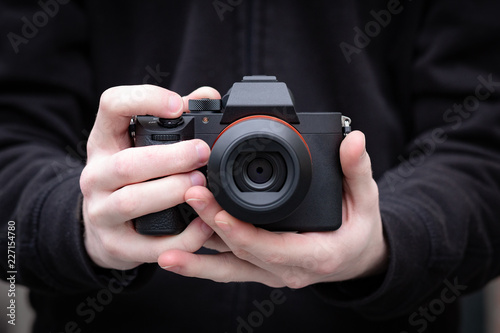Mirrorless digital camera in hand of a young man. Clean image with no brands or signs