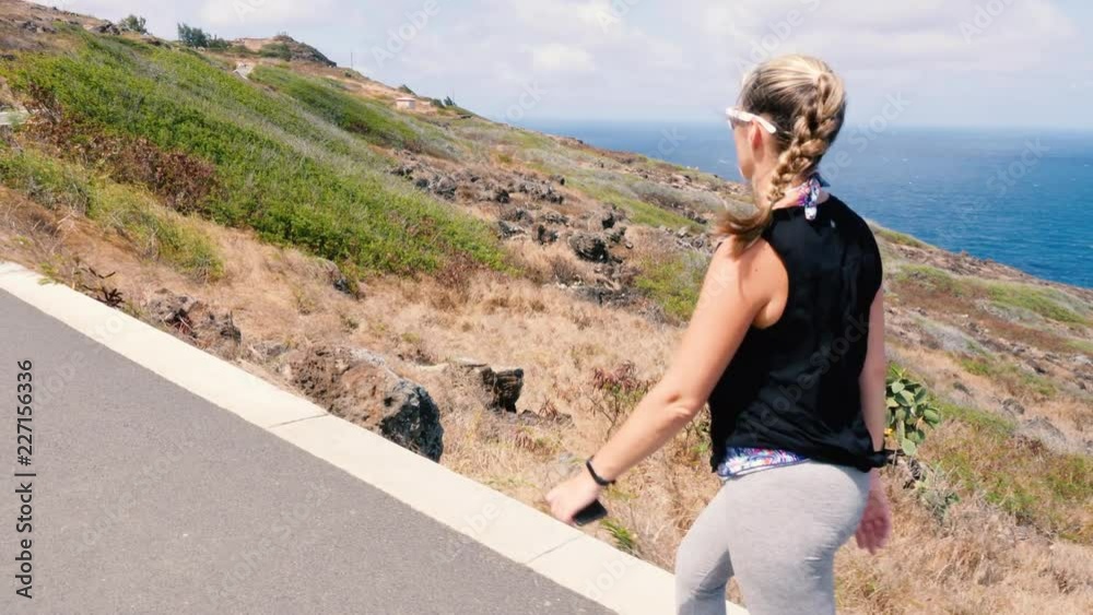 Girl Walking Along Ocean Trail Looking Out. a rising shot of a woman walking on the makapuu trail in Hawaii looking out Girl Walking Along Ocean Trail Looking Out. a rising shot of a woman walking on the makapuu trail in Hawaii looking out
