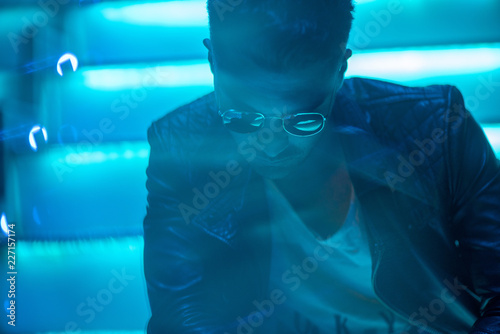 Cinematic portrait of Handsome man with sunglasses and neon lights