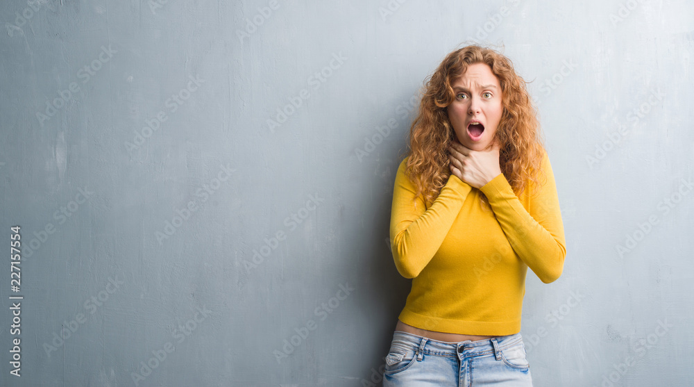 Young redhead woman over grey grunge wall shouting and suffocate because painful strangle. Health problem. Asphyxiate and suicide concept. Young redhead woman over grey grunge wall shouting and suffocate because painful strangle. Health problem. Asphyxiate and suicide concept.