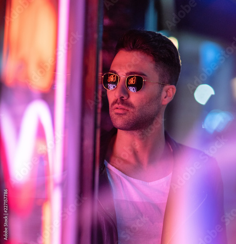 Cinematic portrait of Handsome man with sunglasses and neon lights