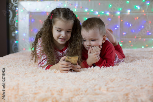 children in Christmas pajamas playing smartphone