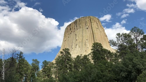 Medium close up time lapse shot of the Devil’s Tower in Wyoming, with thick white clouds moving over it photo