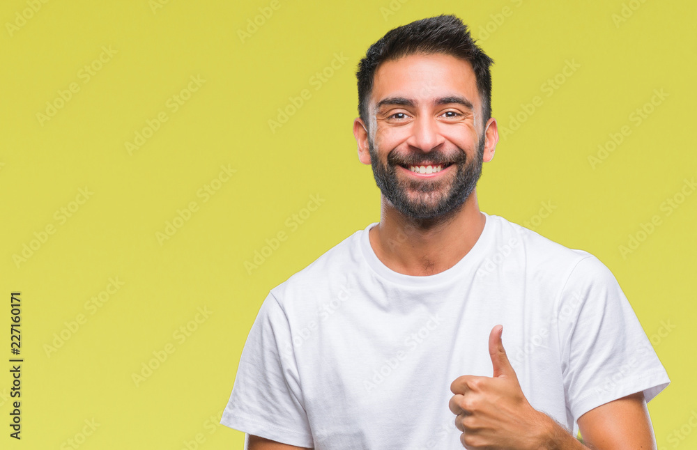 Adult hispanic man over isolated background doing happy thumbs up gesture with hand. Approving expression looking at the camera with showing success.