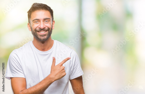 Adult hispanic man over isolated background cheerful with a smile of face pointing with hand and finger up to the side with happy and natural expression on face looking at the camera.