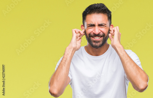 Adult hispanic man over isolated background covering ears with fingers with annoyed expression for the noise of loud music. Deaf concept. © Krakenimages.com