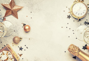 Christmas or New Year composition, frame, pink background with gold Christmas decorations, stars, snowflakes, balls, alarm clock, gift box and bottle of champagne, top view