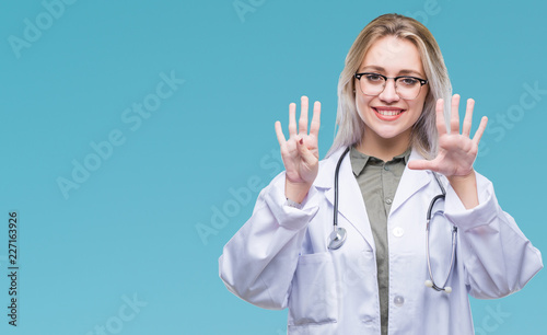 Young blonde doctor woman over isolated background showing and pointing up with fingers number nine while smiling confident and happy.