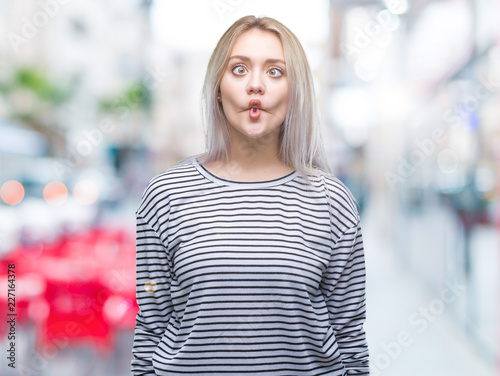 Young blonde woman over isolated background making fish face with lips, crazy and comical gesture. Funny expression.