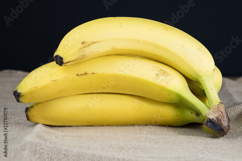 BANANAS ON BROWN SACKCLOTH WITH BLACK BACKGROUND
