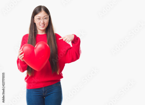 Young Chinese woman wearing graduate uniform red heart with surprise face pointing finger to himself