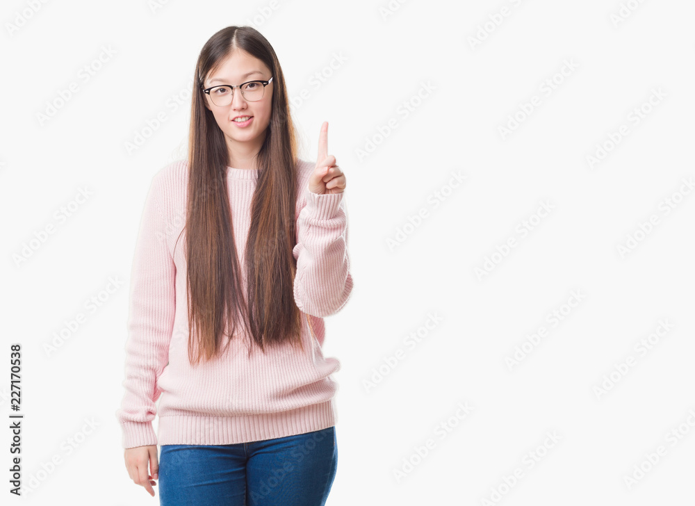 Young Chinese woman over isolated background wearing glasses showing and pointing up with finger number one while smiling confident and happy. Young Chinese woman over isolated background wearing glasses showing and pointing up with finger number one while smiling confident and happy.