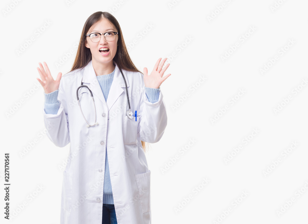 Young Chinese doctor woman over isolated background crazy and mad shouting and yelling with aggressive expression and arms raised. Frustration concept. Young Chinese doctor woman over isolated background crazy and mad shouting and yelling with aggressive expression and arms raised. Frustration concept.