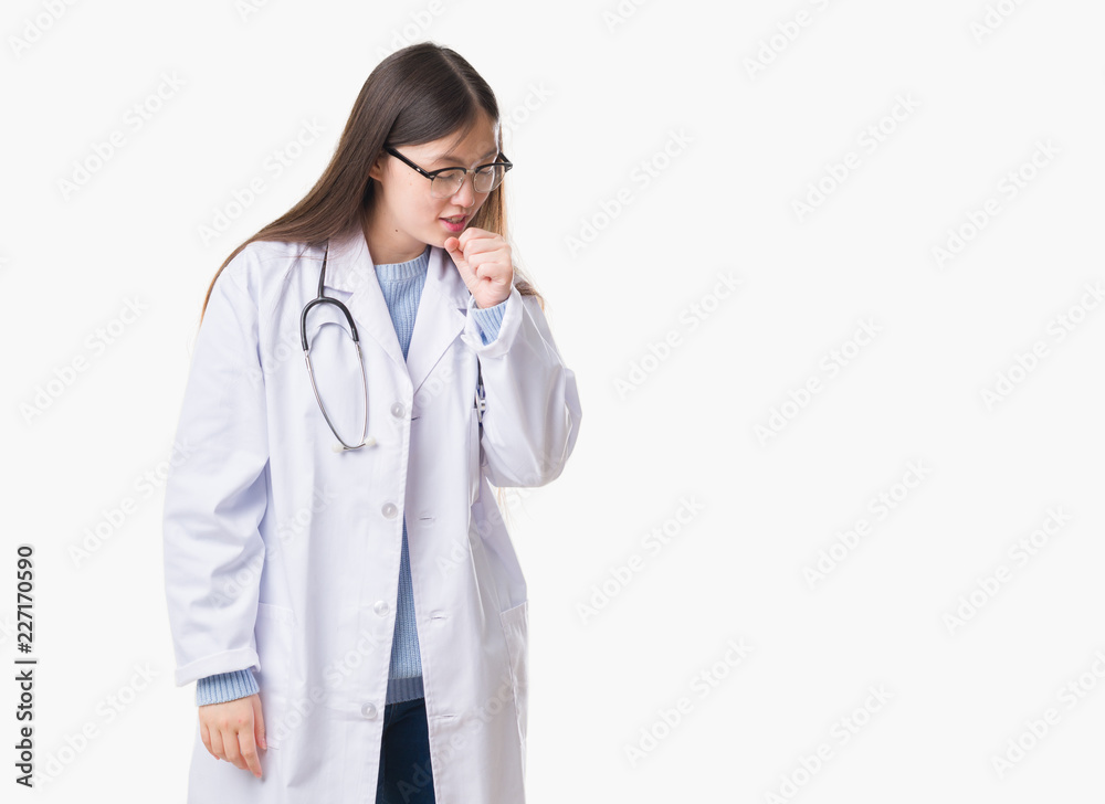 Young Chinese doctor woman over isolated background feeling unwell and coughing as symptom for cold or bronchitis. Healthcare concept. Young Chinese doctor woman over isolated background feeling unwell and coughing as symptom for cold or bronchitis. Healthcare concept.
