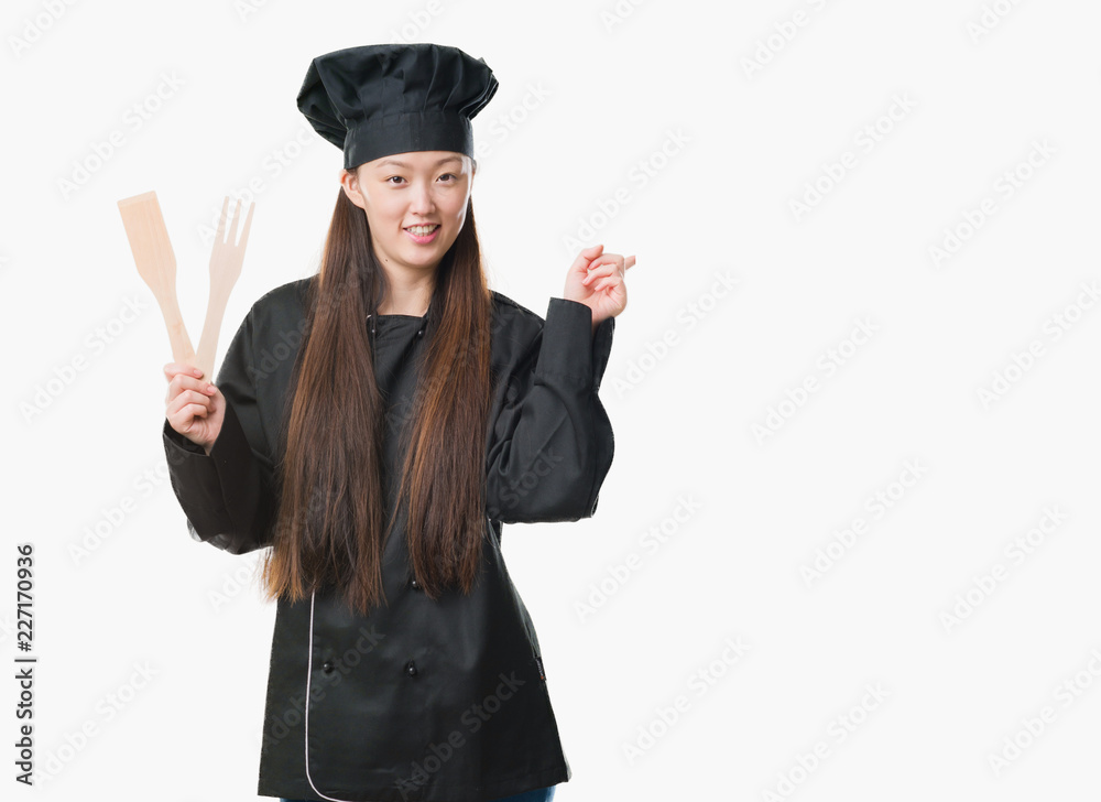 Young Chinese woman over isolated background wearing chef uniform very happy pointing with hand and finger to the side Young Chinese woman over isolated background wearing chef uniform very happy pointing with hand and finger to the side