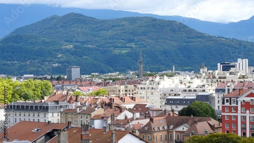 View on the rooftops of the city of Grenoble, with the tiles of the buildings. It is a city in the south-east of France. There are the mountains in the background.