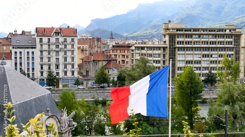French flag in the wind. Filmed in the city of Grenoble in the Alps, southeaster, France. In the background, there is moutains.  photo