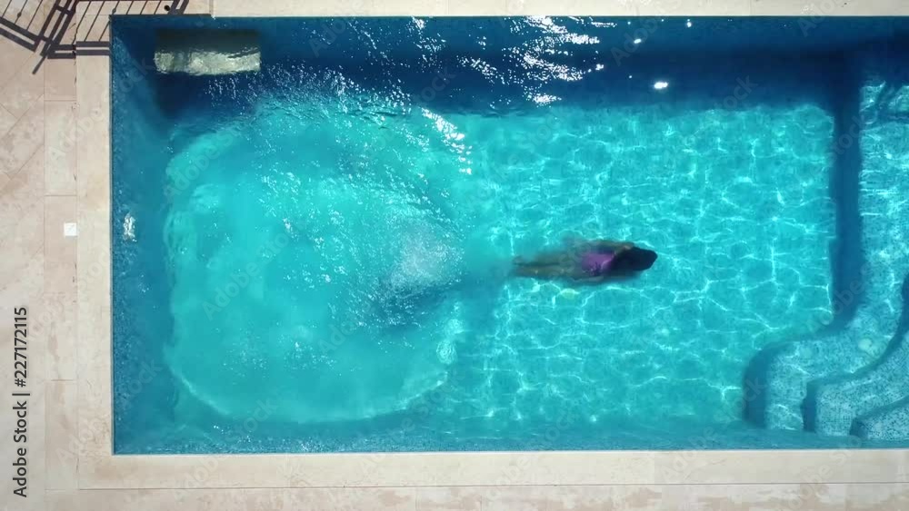 Aerial view of young woman diving into swimming pool.
