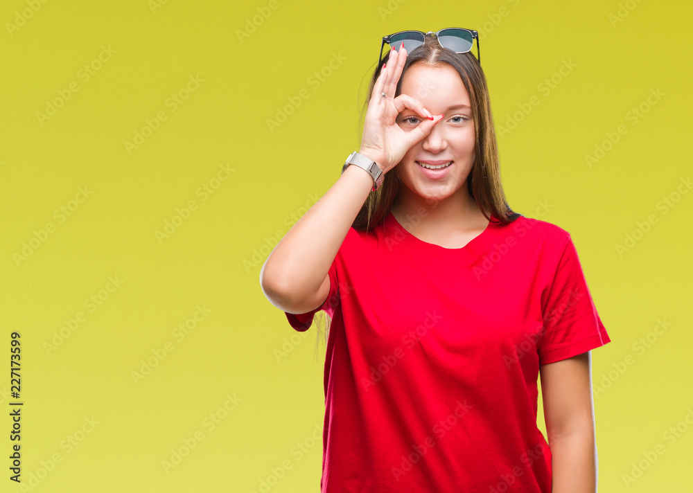 Young beautiful caucasian woman wearing sunglasses over isolated background doing ok gesture with hand smiling, eye looking through fingers with happy face. Young beautiful caucasian woman wearing sunglasses over isolated background doing ok gesture with hand smiling, eye looking through fingers with happy face.