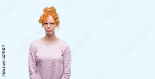 Young redhead woman skeptic and nervous, frowning upset because of problem. Negative person.