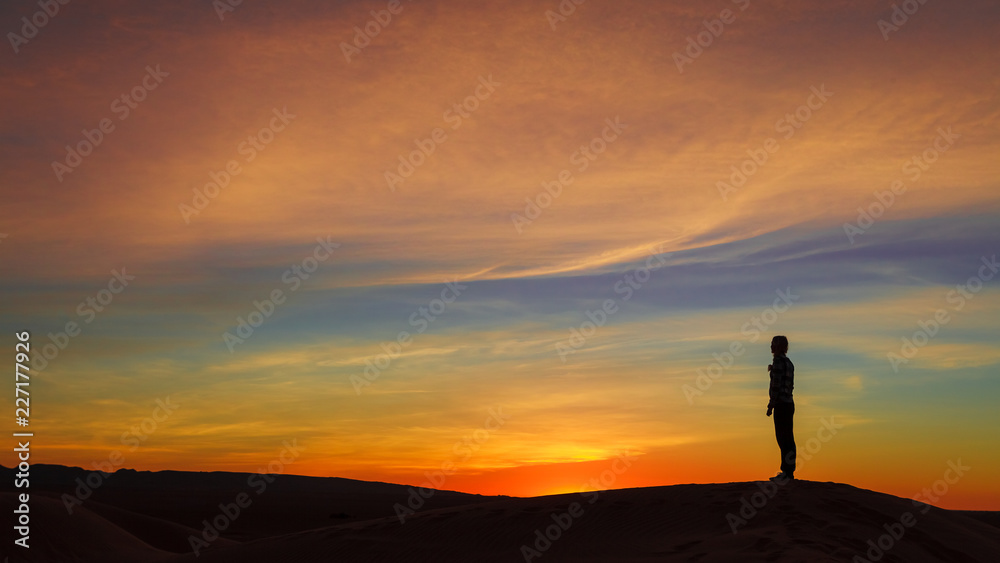 Silhouette of woman posing on sand dune during the sunset