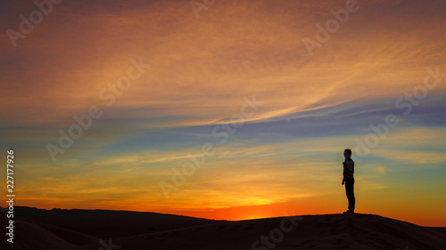 Silhouette of woman posing on sand dune during the sunset © Boy