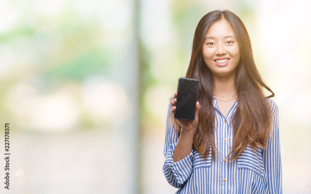 Young asian woman showing blank screen of smartphone over isolated background with a happy face standing and smiling with a confident smile showing teeth Young asian woman showing blank screen of smartphone over isolated background with a happy face standing and smiling with a confident smile showing teeth