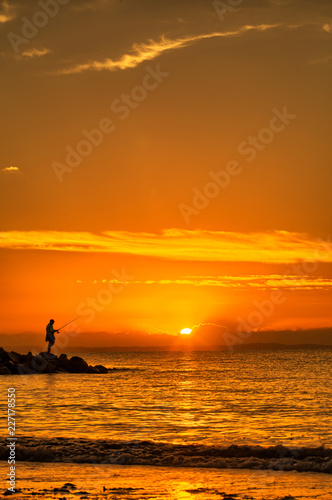 Man fishing off the pier at sunset
