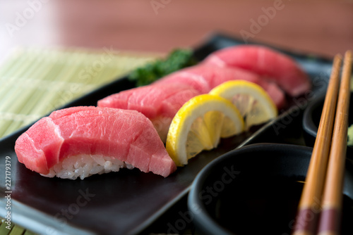 Otoro tuna sushi on black plate along with Japanese sauce and green leaf decoration, Japanese food, close up at sushi ..