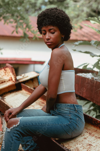 mujer negra afro descendiente sentada sobre metales oxidados
