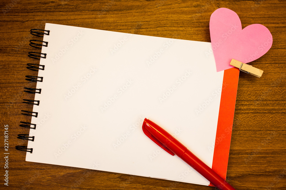 Design business concept Empty template copy space text for Ad website isolated. White notebook with red and black text, pencil, pink paper heart with clip Design business concept Empty template copy space text for Ad website isolated. White notebook with red and black text, pencil, pink paper heart with clip