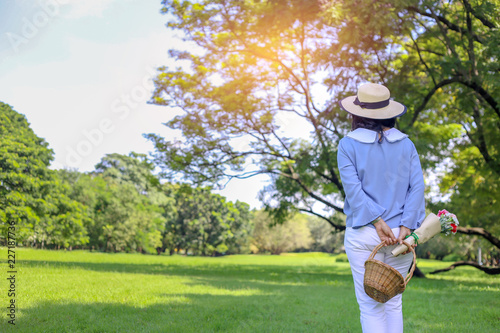 Beautiful lady in blue shirt standing in the green park background