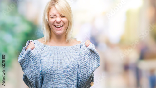 Young beautiful blonde woman wearing winter sweater over isolated background excited for success with arms raised celebrating victory smiling. Winner concept. © Krakenimages.com