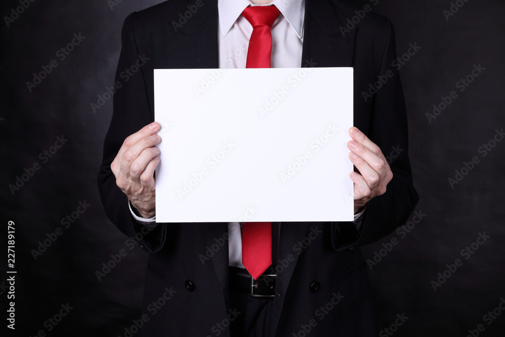 Man in black suit holding a blank paper Man in black suit holding a blank paper