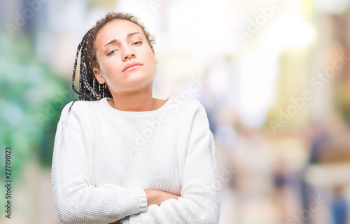 Young braided hair african american girl wearing winter sweater over isolated background skeptic and nervous, disapproving expression on face with crossed arms. Negative person.