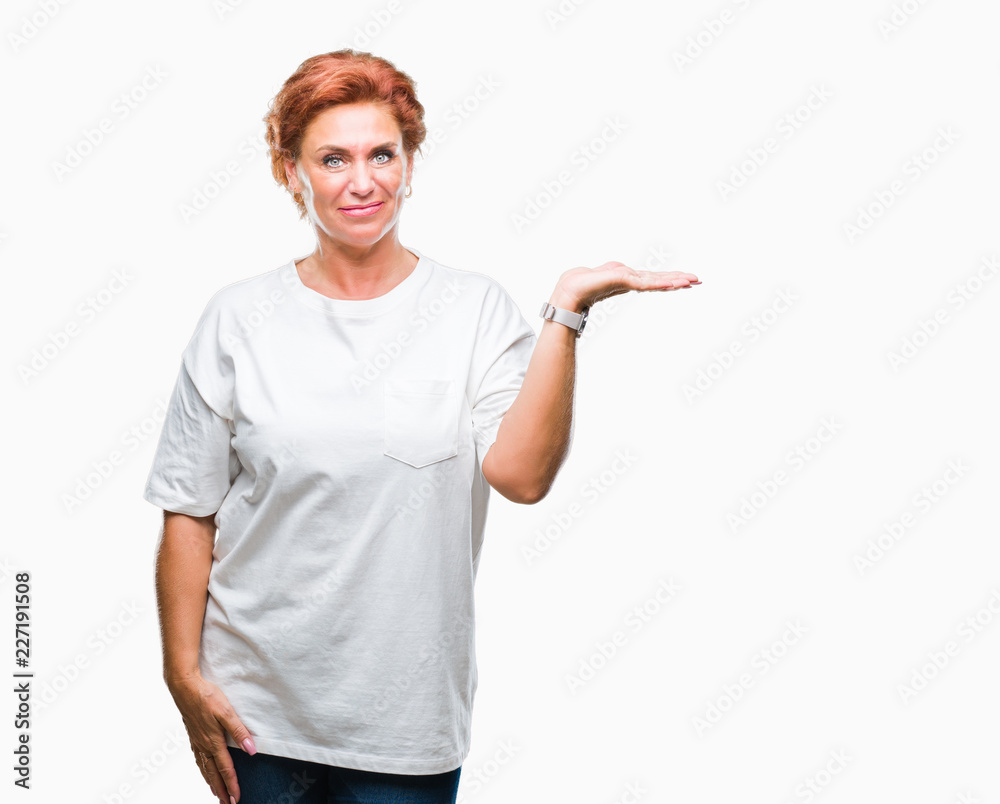 Atrractive senior caucasian redhead woman over isolated background smiling cheerful presenting and pointing with palm of hand looking at the camera. Atrractive senior caucasian redhead woman over isolated background smiling cheerful presenting and pointing with palm of hand looking at the camera.