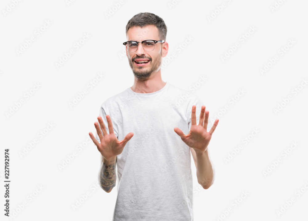 Young tattooed adult man afraid and terrified with fear expression stop gesture with hands, shouting in shock. Panic concept. Young tattooed adult man afraid and terrified with fear expression stop gesture with hands, shouting in shock. Panic concept.