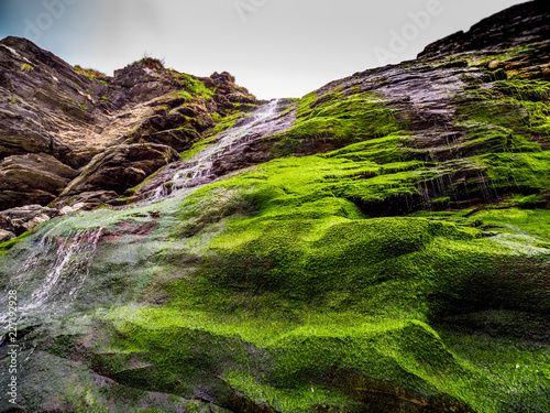 Beautiful waterfall over mossy stones in the Cove of Tintagel in Cornwall