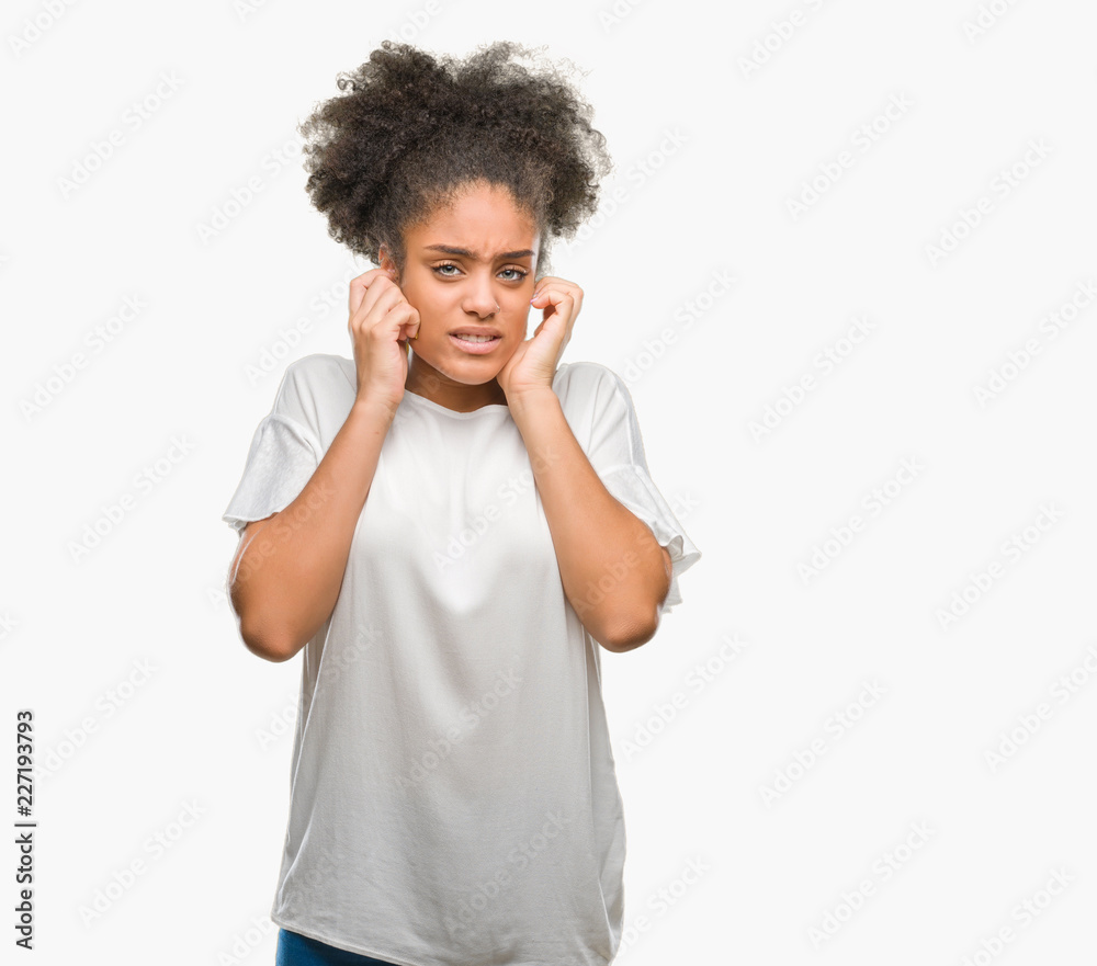 Young afro american woman over isolated background covering ears with fingers with annoyed expression for the noise of loud music. Deaf concept. Young afro american woman over isolated background covering ears with fingers with annoyed expression for the noise of loud music. Deaf concept.
