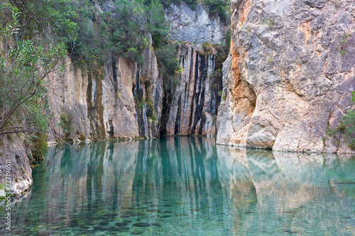 Natural hot springs in a beautiful mountainous canyon in Valencia region of Spain. Landscape of clear water with reflection of surrounding mountains.