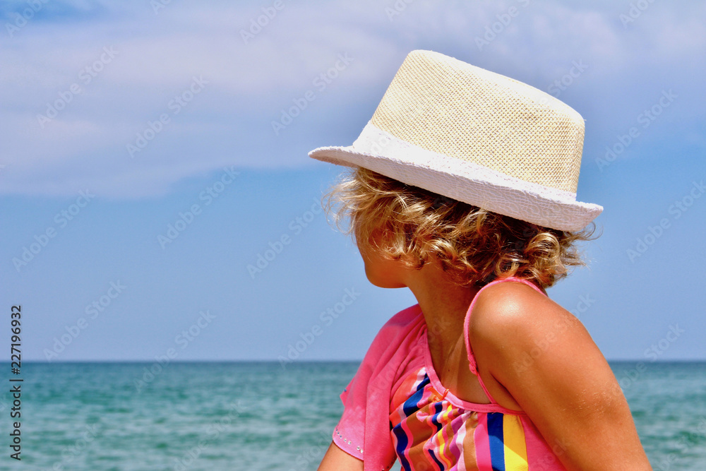Sunny girl with the hat on the beach 