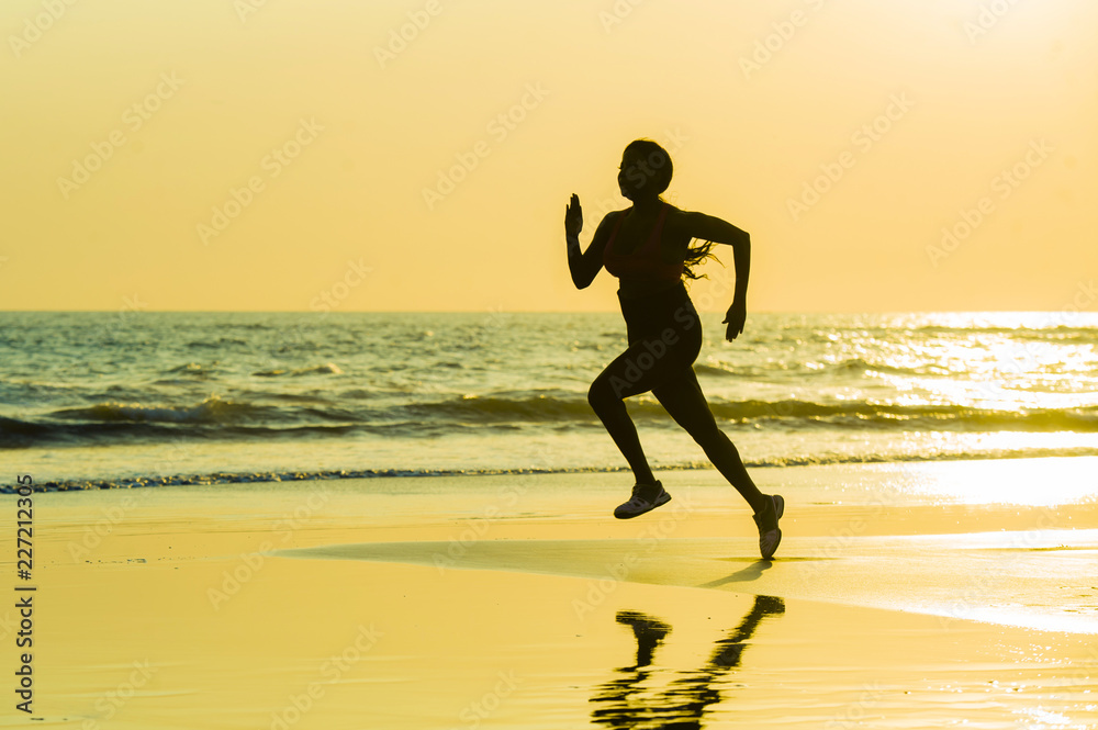 silhouette of young happy and attractive African American runner woman exercising in running fitness sprint workout at beautiful beach jogging and enjoying sunset