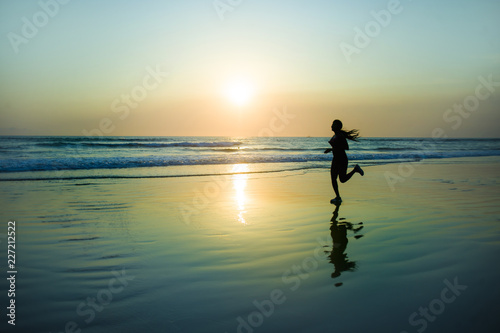 silhouette of young happy and attractive African American runner woman exercising in running fitness workout at beautiful beach jogging and enjoying sunset