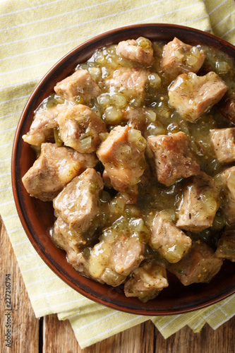 Pork slowly stews with jalapenos, onion, green verde sauce and spices in this flavor-packed Mexican dish closeup on a plate. Vertical top view