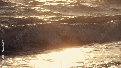 Big waves on a sea beach at sunset. Beautiful waves of slow motion video on the background of the orange sun photo