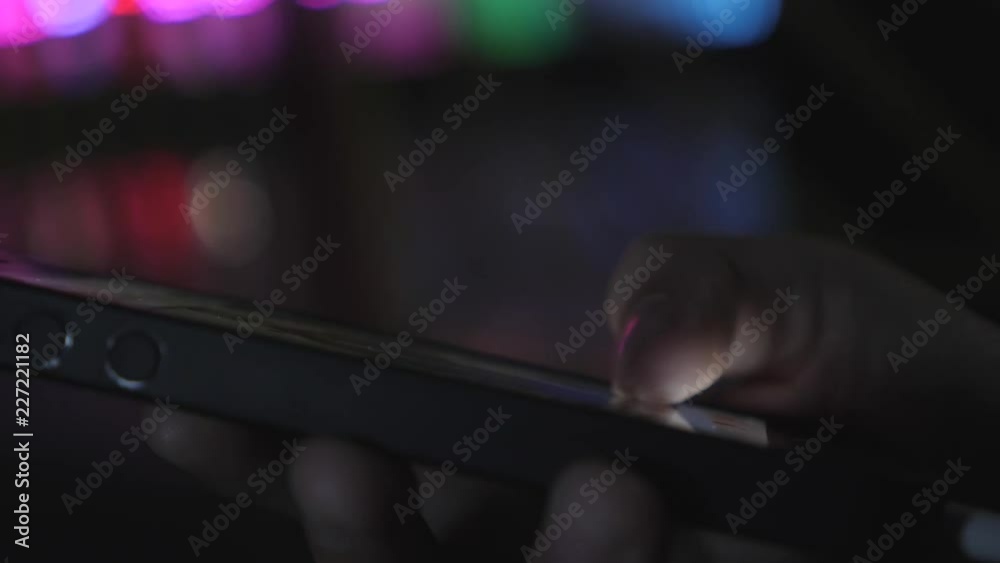 Close-up image of a child's hands using a smartphone at night on a city shopping street, search or social network concept, a hipster man typing a sms message to his friends