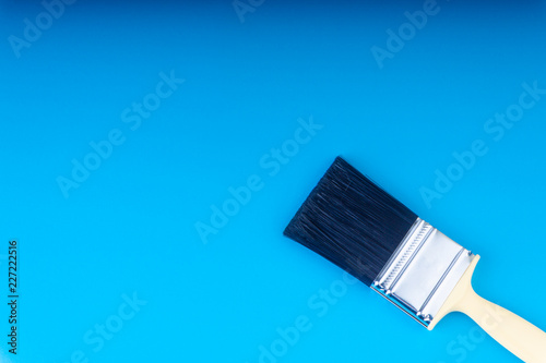 Paint brush on blue colour background with selective focus and crop fragment. Copy space conceptual