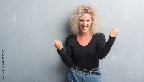 Young blonde woman with curly hair over grunge grey background screaming proud and celebrating victory and success very excited, cheering emotion